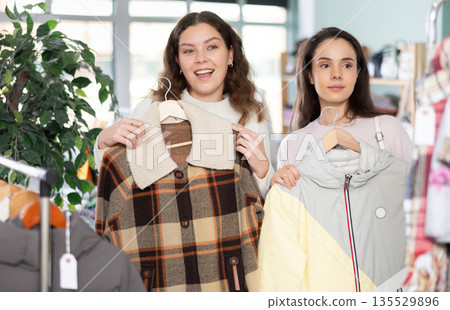 Two young women choosing coat and jacket Two young women choosing coat and jacket 135529896