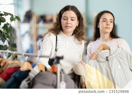 Two girls client pick up and choose clothes, is busy coat or jacket 135529898