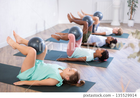 Kids doing pilates with softball Kids doing pilates with softball 135529914