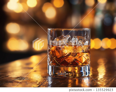 Luxury whiskey or rum cocktail in rocks glass with ice cubes on bar counter against bokeh lights. Premium alcoholic drink presentation, nightlife elegance, refined lifestyle, upscale bar aesthetics. 135529923
