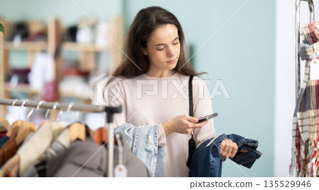Young woman scanning barcode on jeans labels in store Young woman scanning barcode on jeans labels in store 135529946