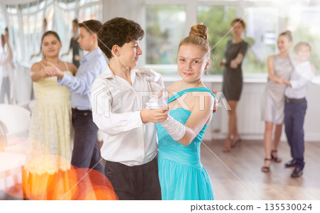 Adolescent ballroom dancers practicing elegant dance moves in pairs 135530024