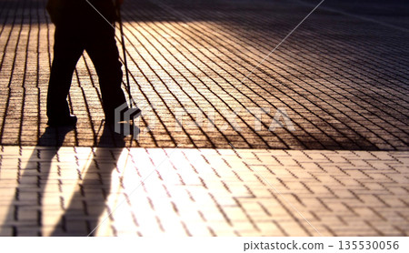 夕陽照耀下，人們走在人行道上 135530056