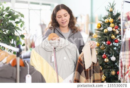Young woman choosing coat and jacket in clothing store Young woman choosing coat and jacket in clothing store 135530078