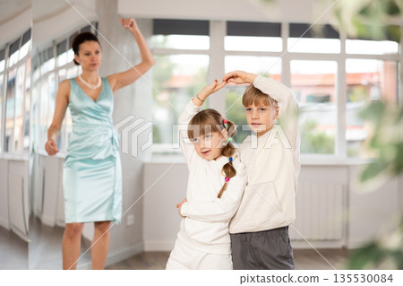 Tween boy and girl performing waltz in pair in dance hall Tween boy and girl performing waltz in pair in dance hall 135530084