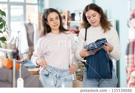 Young girls choosing jeans pantaloons in clothing store 135530088