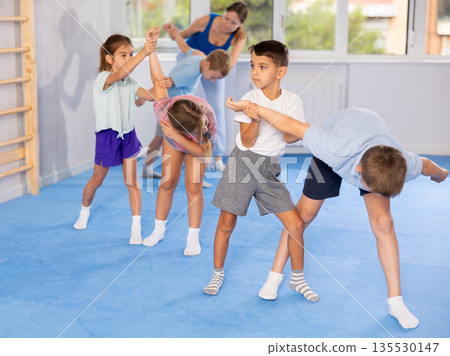 Kids in sportswear exercising self-protection techniques in pair during class Kids in sportswear exercising self-protection techniques in pair during class 135530147