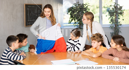 Teacher holds the flag of Czech in her hands and tells the students about country Teacher holds the flag of Czech in her hands and tells the students about country 135530174