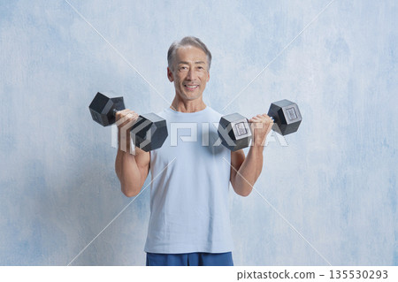 Senior man doing muscle training with dumbbells, looking at the camera 135530293