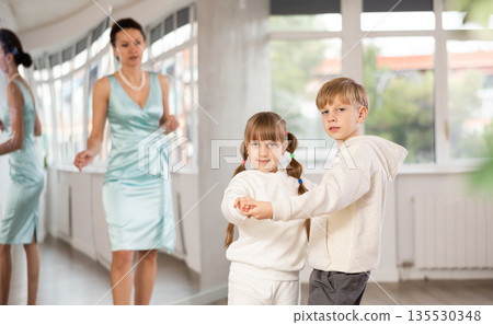 Tween boy and girl performing waltz in pair in dance hall Tween boy and girl performing waltz in pair in dance hall 135530348
