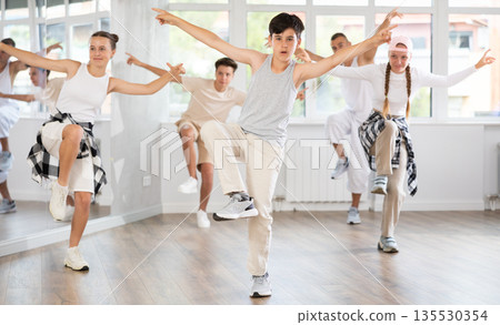 Teenage boy practicing hip hop reject step in training hall Teenage boy practicing hip hop reject step in training hall 135530354
