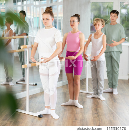 Teenage boys and girls practicing first position of ballet in dancehall 135530378