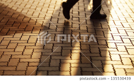 夕陽照耀下，人們走在人行道上 135530439