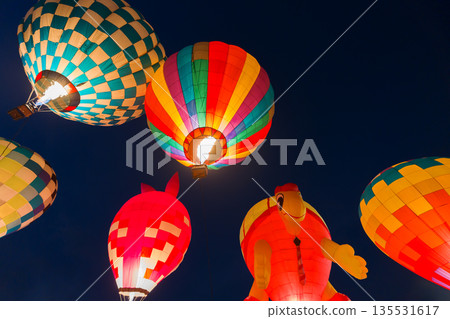 colorful hot air balloons glowing against dark night sky 135531617