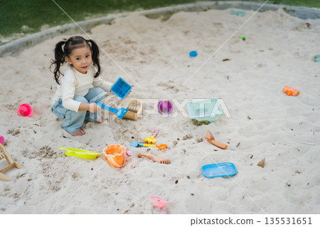 happy child girl playing sand with toy on playground 135531651