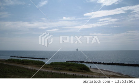 A hill overlooking the sea, blue sky, and oil fields 135532602