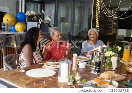 Family enjoying dinner together, sharing stories and laughter at festive table Family enjoying dinner together, sharing stories and laughter at festive table 135532718