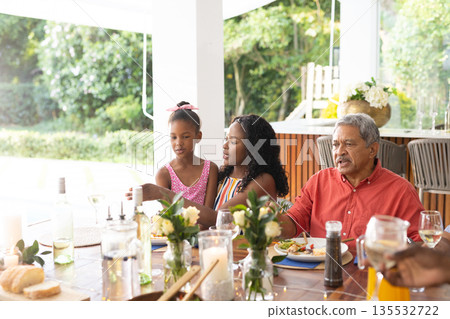 Family enjoying meal together at home, sharing stories and laughter around table Family enjoying meal together at home, sharing stories and laughter around table 135532722