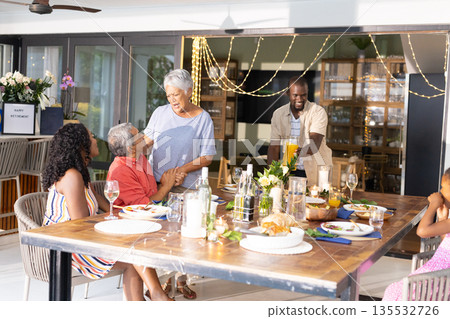 Family sharing festive meal, laughing and talking around dining table at home 135532726