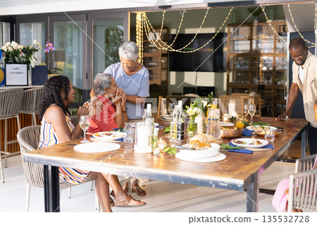 Sharing dinner, African American family laughing and creating joyful moments at home Sharing dinner, African American family laughing and creating joyful moments at home 135532728