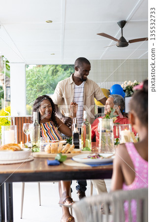 Sharing meal outdoors, African American family laughing and conversing together Sharing meal outdoors, African American family laughing and conversing together 135532733