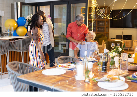 Family celebrating together at home, sharing laughter and joy around dinner table Family celebrating together at home, sharing laughter and joy around dinner table 135532735