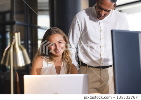 Colleagues collaborating on laptop in modern office, smiling and discussing project Colleagues collaborating on laptop in modern office, smiling and discussing project 135532767