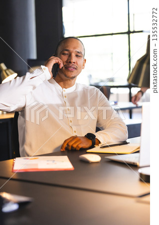 Businessman in white shirt talking on smartphone at modern office desk 135532772