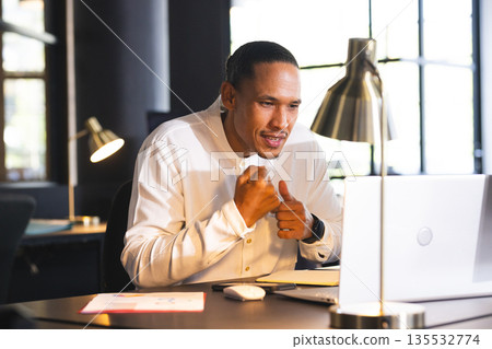 Businessman in office celebrating success while video conferencing on laptop Businessman in office celebrating success while video conferencing on laptop 135532774