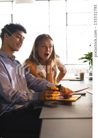 Colleagues discussing project at office desk, sharing ideas and smiling 135532795