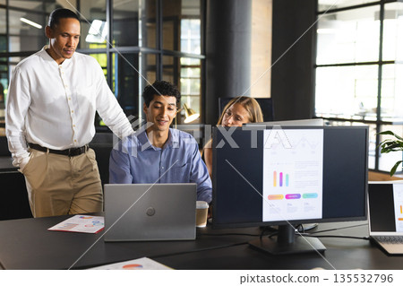 Business team collaborating on project with laptops and charts in modern office 135532796
