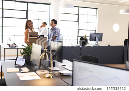 Colleagues discussing project in modern office, smiling and collaborating together 135532832