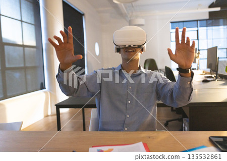 In office, man using VR headset interacting with virtual environment enthusiastically 135532861
