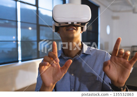 Man using VR headset in modern office, exploring virtual reality technology 135532863