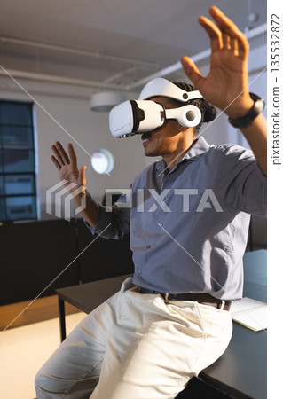 Man using VR headset in office, engaging with virtual environment enthusiastically 135532872