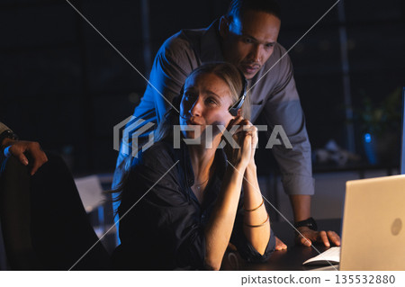 Business professionals collaborating at night, discussing strategy in modern office Business professionals collaborating at night, discussing strategy in modern office 135532880