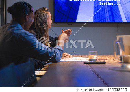 Colleagues discussing presentation in modern conference room during evening meeting 135532925