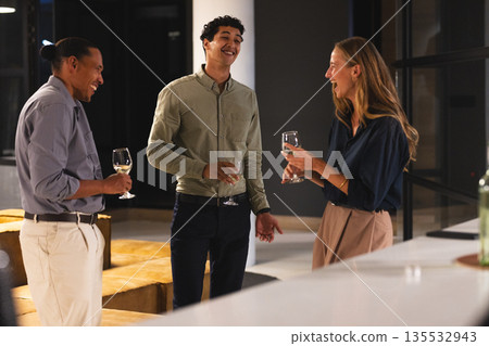Networking at office event, professionals conversing and holding wine glasses Networking at office event, professionals conversing and holding wine glasses 135532943