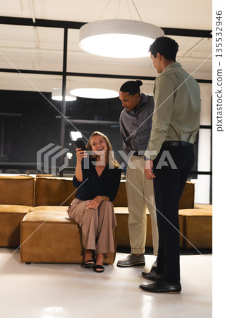 In modern office, woman showing smartphone while discussing ideas with professionals In modern office, woman showing smartphone while discussing ideas with professionals 135532946