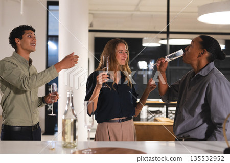 Colleagues celebrating success with champagne in modern office at night Colleagues celebrating success with champagne in modern office at night 135532952