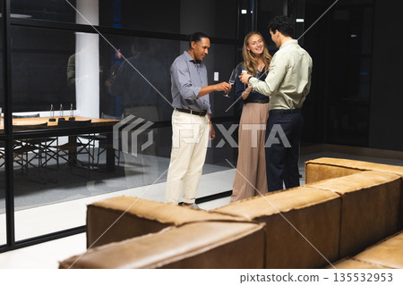 Business professionals discussing project in modern office lounge at night 135532953