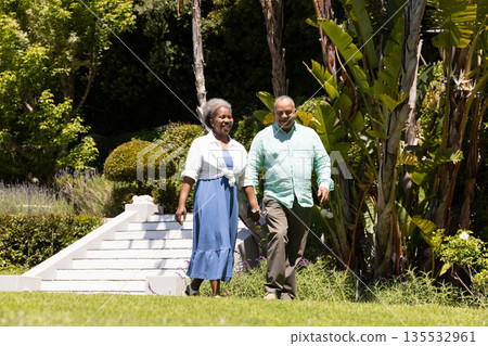 Senior couple walking joyfully in lush garden, enjoying sunny day together Senior couple walking joyfully in lush garden, enjoying sunny day together 135532961