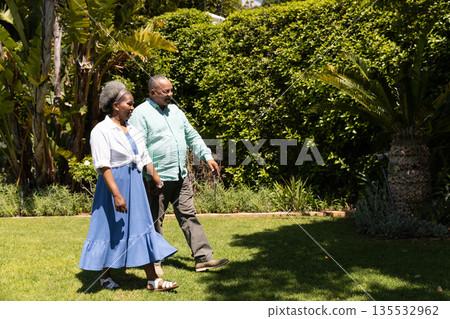 Senior couple walking in garden, enjoying sunny day and each other's company Senior couple walking in garden, enjoying sunny day and each other's company 135532962