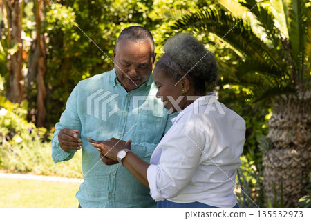 Senior couple enjoying time together in garden, smiling and sharing moment Senior couple enjoying time together in garden, smiling and sharing moment 135532973