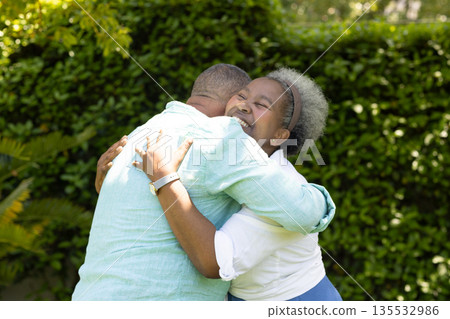 Senior couple embracing joyfully in garden, sharing warm and loving hug 135532986