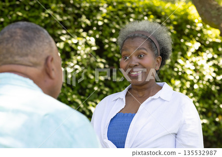 African American senior couple enjoying conversation outdoors, smiling and engaged 135532987