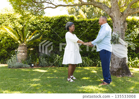 Senior couple holding hands in garden, smiling and enjoying sunny day together Senior couple holding hands in garden, smiling and enjoying sunny day together 135533008