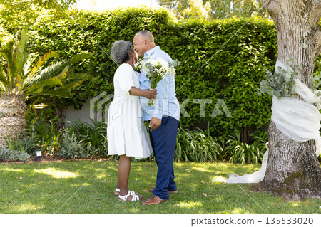 Senior couple embracing and kissing in garden, celebrating love and togetherness Senior couple embracing and kissing in garden, celebrating love and togetherness 135533020