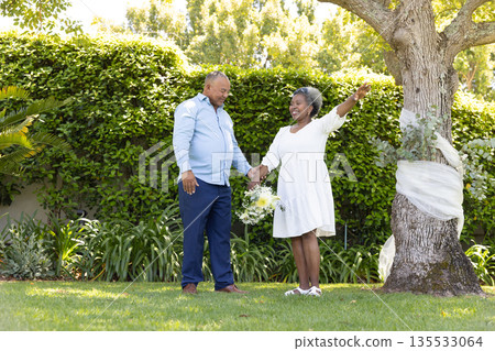 Senior couple celebrating outdoors, holding hands and smiling under tree Senior couple celebrating outdoors, holding hands and smiling under tree 135533064