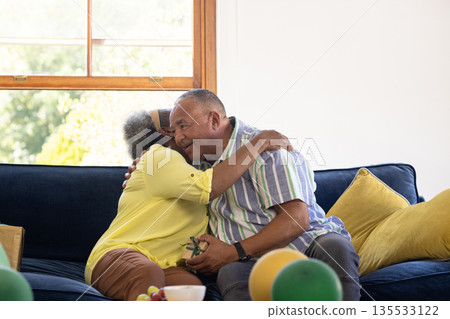 Senior couple embracing on sofa, sharing joyful moment at home Senior couple embracing on sofa, sharing joyful moment at home 135533122